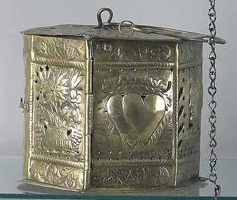 Foot Warmers - An 18th century Dutch brass hexagonal wedding presentation foot warmer with decorations of hearts, flowers, and busts of man and woman which sold at Pook and Pook September 23, 2003 for $2,530.
