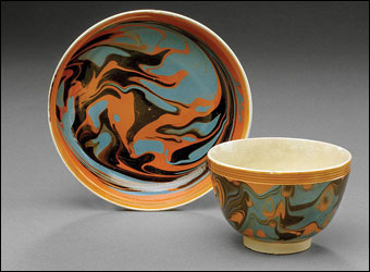 Mochaware - Unusual British creamware mochawear handleless cup and saucer, ca. 1800. Each slip marbled in black and slate blue on a pumpkin field within rouletted orange-glazed reeded borders. Diameter 3 1/2