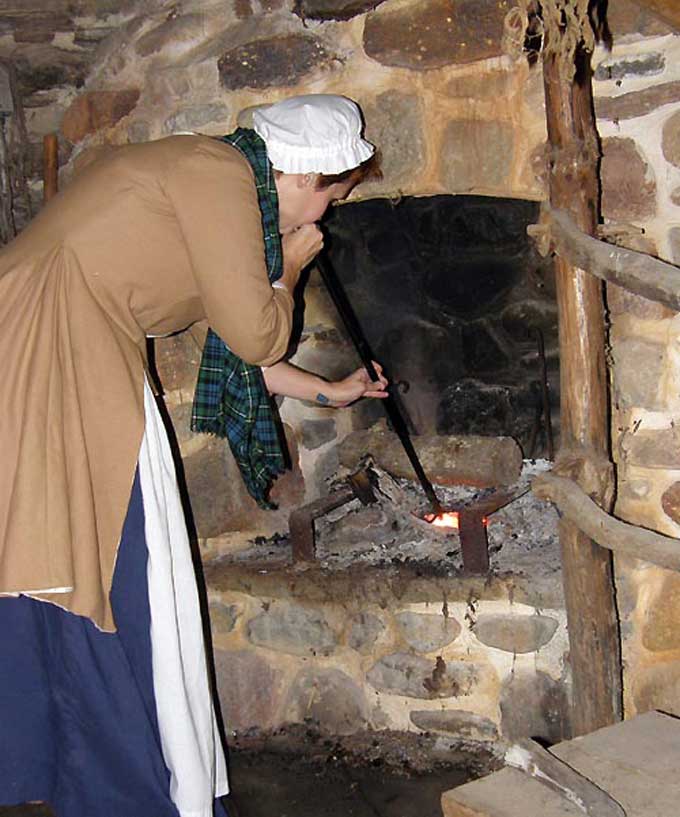 Salem, NJ Yuletide Tour - A lady keeping the fire going in the log cabin at Johan Printz Memorial Park
